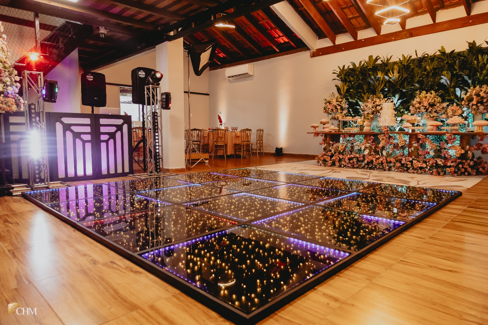 Pista de dança iluminada com mesa de doces ao fundo